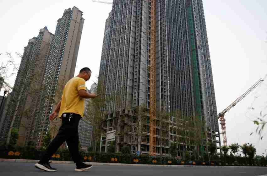 رجل يسير أمام مبانٍ سكنية غير مكتملة في واحة إيفرغراند، وهو مجمع سكني طورته مجموعة إيفرغراند، في لويانغ في الصين، في 15 سبتمبر 2021. الصورة: كارلوس جارسيا رولينز، رويترز.